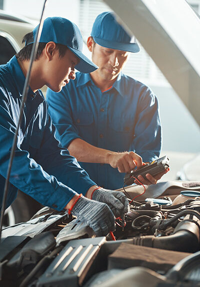 Serious professional Vietnamese technicians setting multimeter to measure voltage of battery