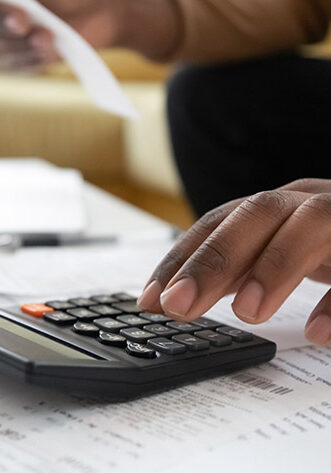 Close up black man hand using calculator and laptop for calculating finance. African american businessman taxing, accounting, statistics and credit analytic for mortgage payment.